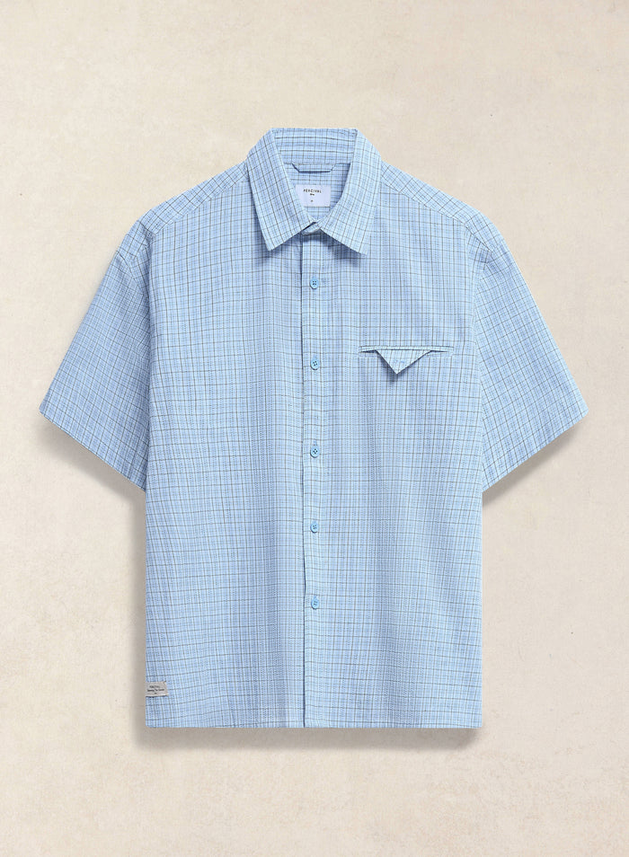 The Percival Hinsley boxy short sleeve shirt in blue check cotton, featuring a unique geometric chest pocket detail.