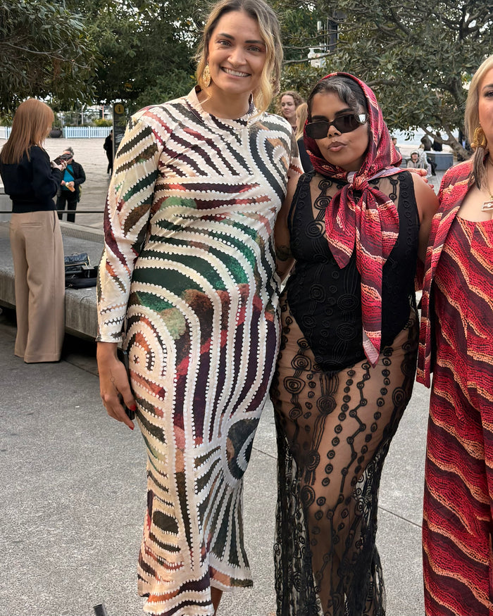 Two Aboriginal women posing outdoors, All wearing Aboriginal artwork clothing