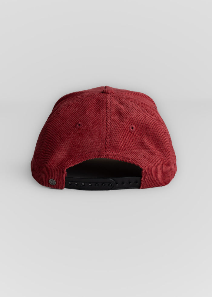 Back view of a red corduroy cap with an adjustable black strap, set against a plain white background.