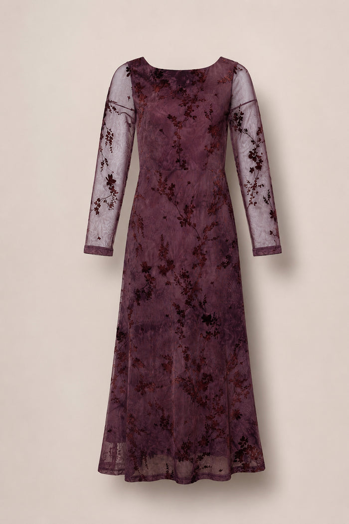 The Blair Dress in Maroon Burnout Floral by Ivy City Co is a long-sleeved, floor-length maxi evening dress crafted from sheer mauve fabric with an elegant maroon burnout floral velvet pattern. It features a fitted bodice and a slight flare at the hem for a sophisticated silhouette.