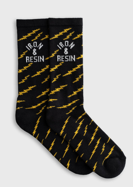 Black socks with yellow lightning bolts and "Iron & Resin" text, showcasing a bold, energetic design on a plain background.