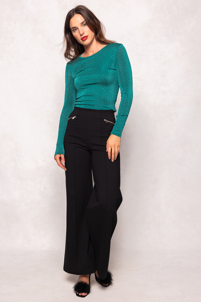 Woman wearing a teal top and black pants on a white background