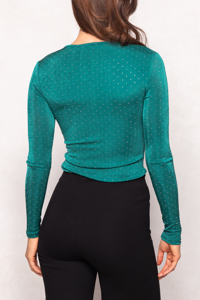 Green long-sleeve top worn by a person on a white background