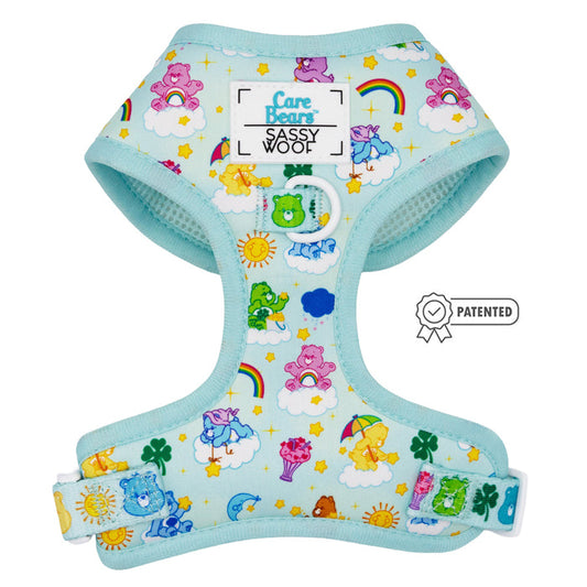 The Sassy Woof Dog Adjustable Harness - Care Bears™ Care-a-Lot features light blue fabric with colorful Care Bears, rainbows, clouds, suns, and clovers. Includes official labels, a patented badge, and is part of the Puppy Growth Pawtection Plan.