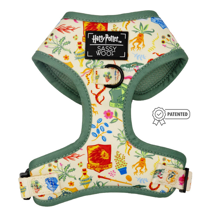 The Dog Adjustable Harness - Harry Potter™ Herbology by Sassy Woof features house crests and magical designs on cream with green trim. “Harry Potter Sassy Woof” appears on a black patch, with a patented graphic beside the harness.