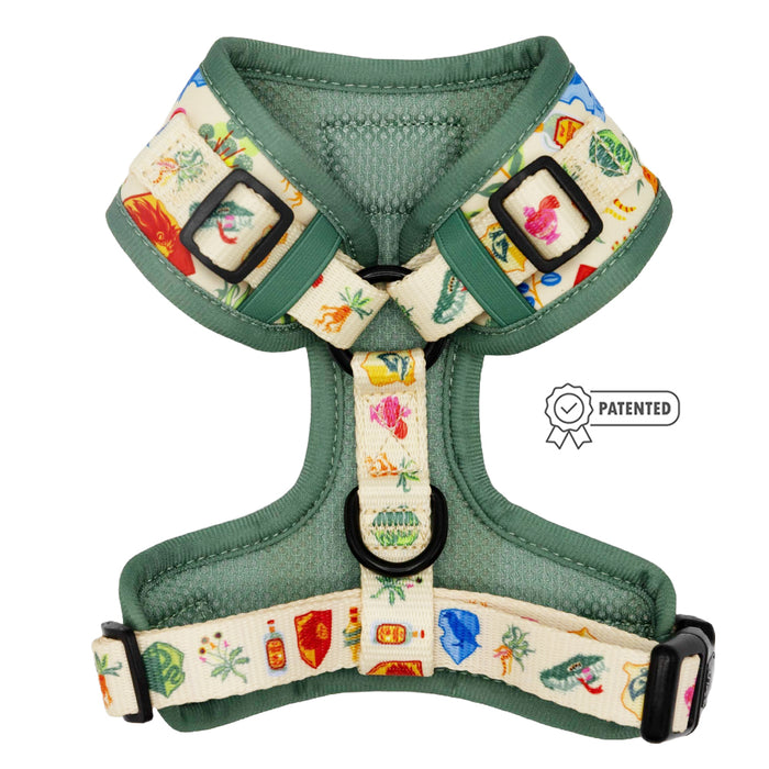 The Sassy Woof Dog Adjustable Harness - Harry Potter™ Herbology features green and cream colors with cartoon herbology prints, adjustable straps, black buckles, metal rings, and a patented badge icon on the right side.