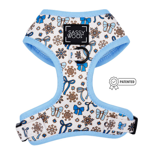 The Sassy Woof Dog Adjustable Harness - Let it Bow features blue and brown snowflakes, bows, and ornaments, with a front SASSY WOOF label and patent badge illustration—a stylish coquette harness for your pup!.