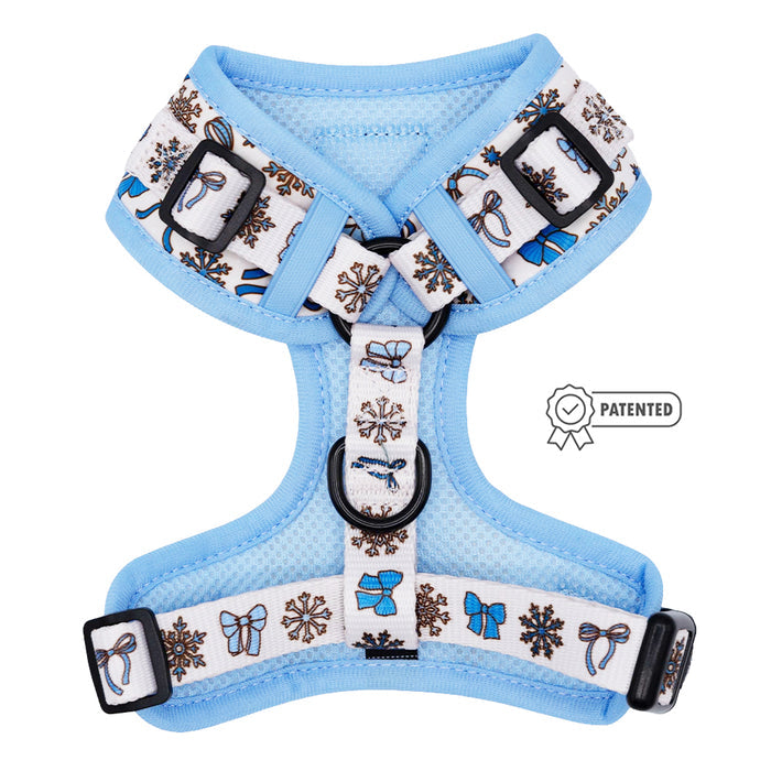 The Sassy Woof Dog Adjustable Harness - Let it Bow features blue fabric, white straps, blue bows, brown snowflakes, black buckles, and a Patented label—perfect for pups on the growth pawtection plan!.