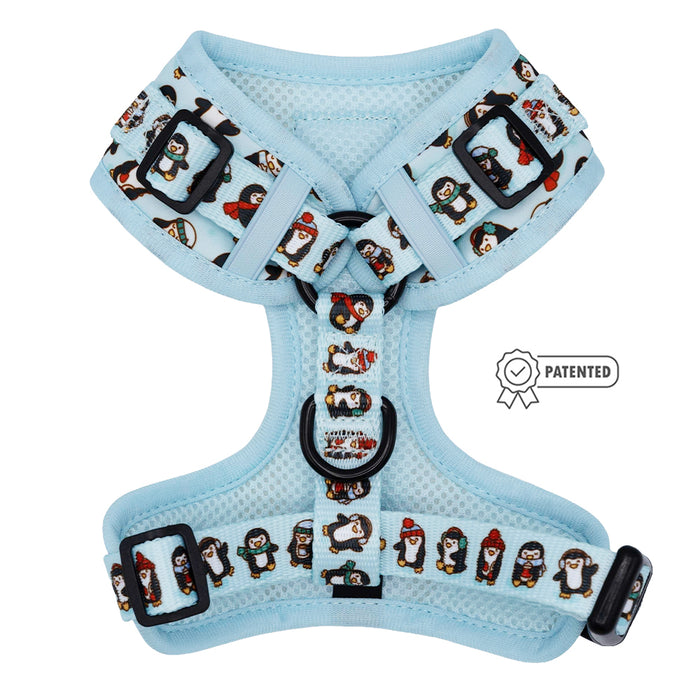 The Sassy Woof Dog Adjustable Harness - Winter Waddleland features light blue mesh, black buckles, and cute cartoon penguins in winter gear. A Patented badge on the right adds a playful touch, making it a fun winter accessory for your pup.