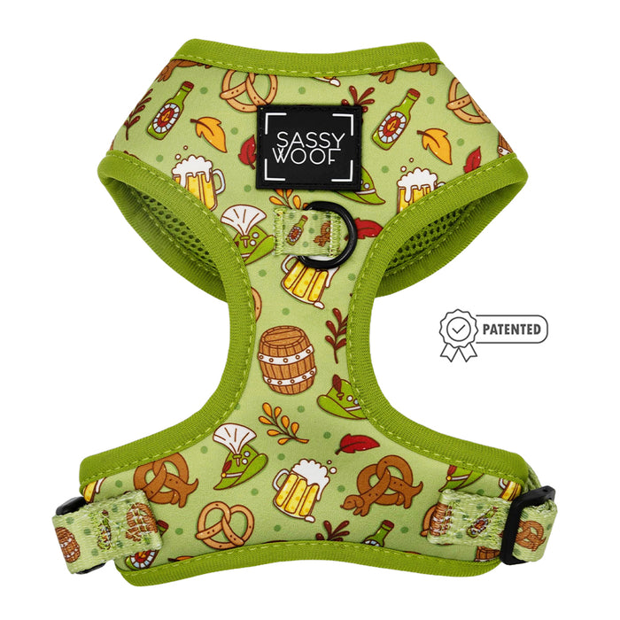 The Sassy Woof Dog Adjustable Harness - Wurst Behavior features a green design with beer mugs, pretzels, bottles, and barrels, adjustable black-strapped buckles, a black Sassy Woof logo, and a "Patented" badge displayed to the right.