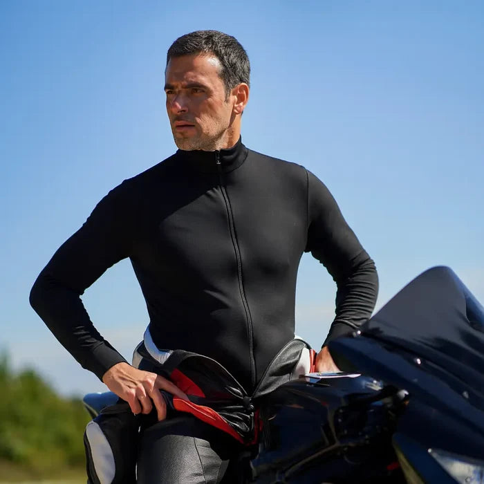 Man straddling his motorbike with his upper leathers peeled back to show the Sub Zero Factor 2 thermal mid layer onesie in black worn underneath