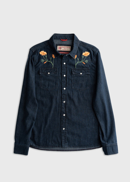 Dark denim shirt with orange floral embroidery on shoulders, featuring buttoned pockets and a classic collar, laid flat on white.