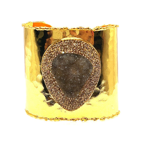 Gold-tone adjustable wide cuff bracelet with an oversized gemstone center framed by sparkling crystal accents.