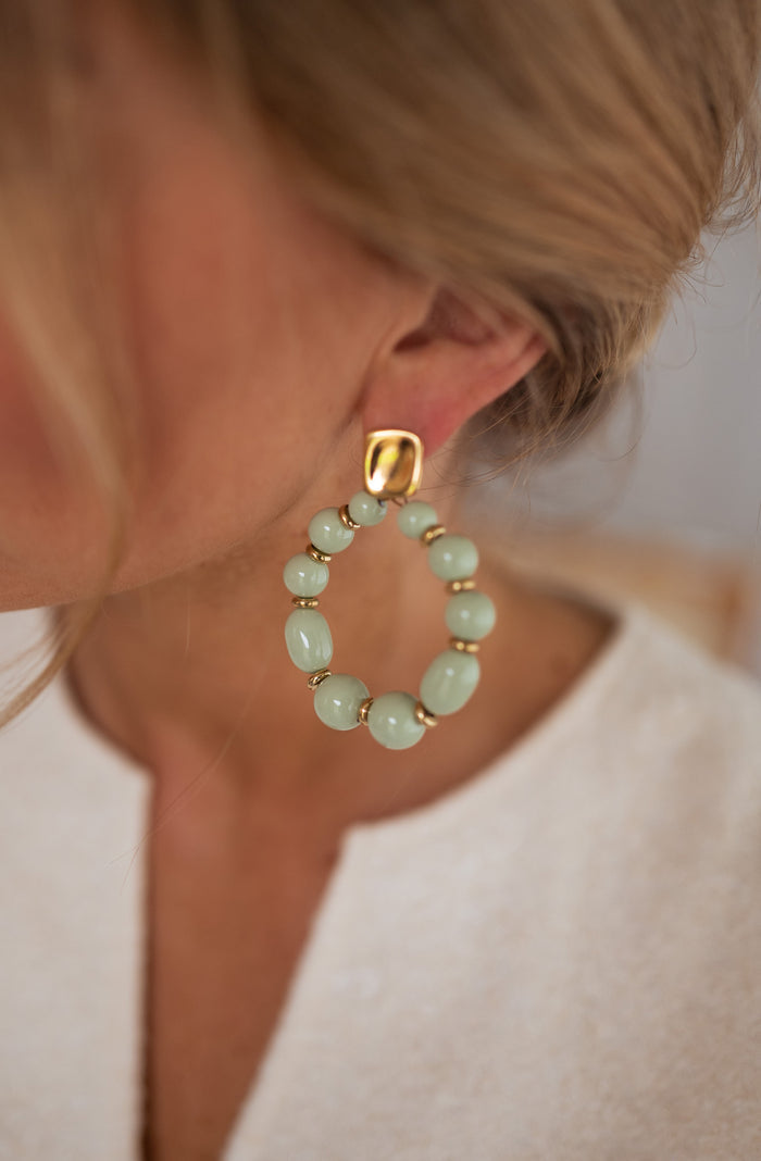 Golden and green Loda hoop drop earrings worn
