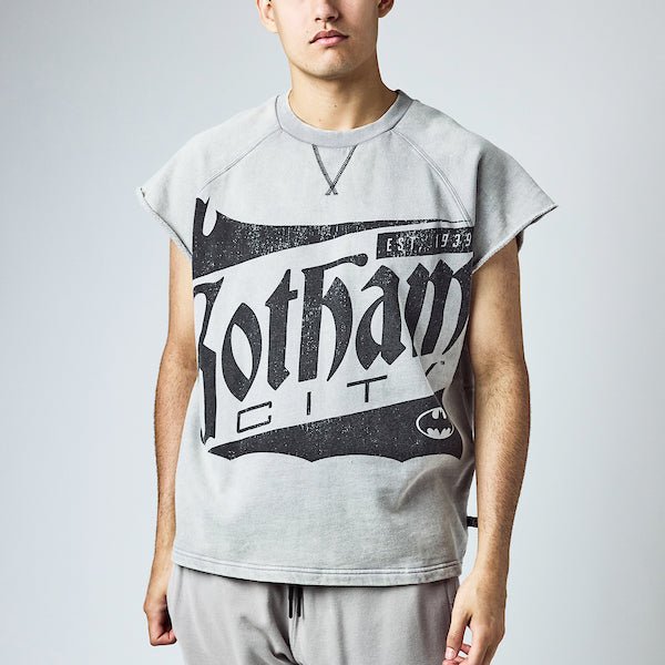 Sleeveless light gray sweatshirt featuring a large vintage-style graphic of "Gotham City" with a bat silhouette and the text "Est. 1939" in distressed black print. A small Batman logo is also present at the bottom right of the design