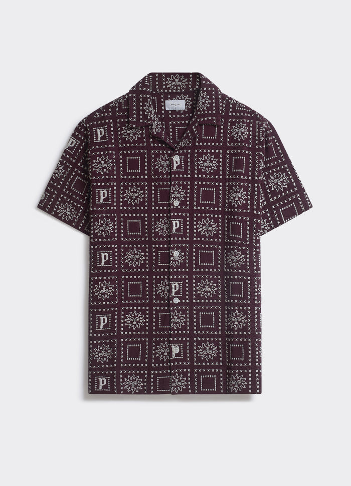 The Percival Heaton Shirt in burgundy, featuring a white geometric motif and camp collar, shown flat-laid.
