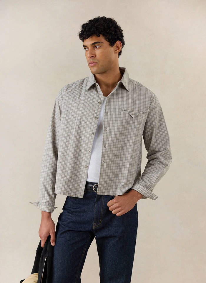 A model wears the cream Percival Hinsley Boxy Long Sleeve Shirt in cotton check, styled with dark jeans and a vest.