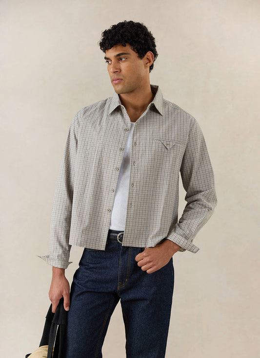 A model wears the cream Percival Hinsley Boxy Long Sleeve Shirt in cotton check, styled with dark jeans and a vest.