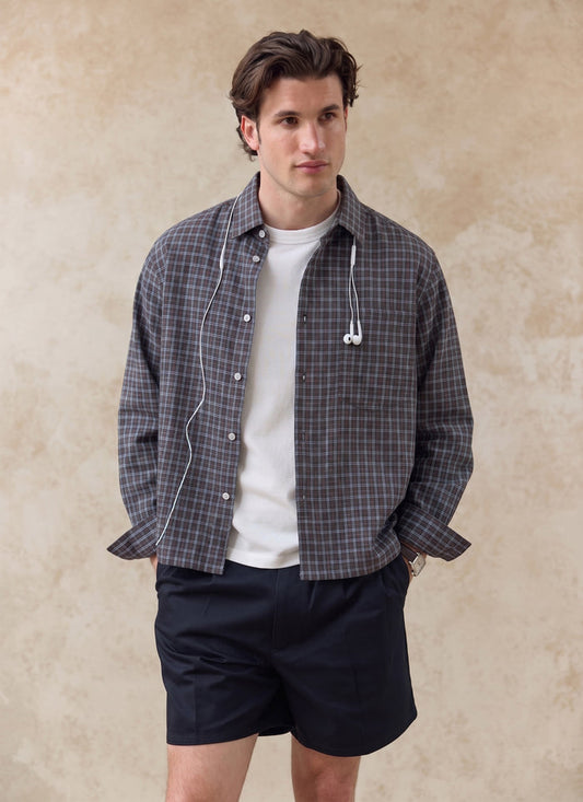 Brown Percival Hinsley checked boxy cotton shirt, worn unbuttoned over a white t-shirt and shorts on a model.