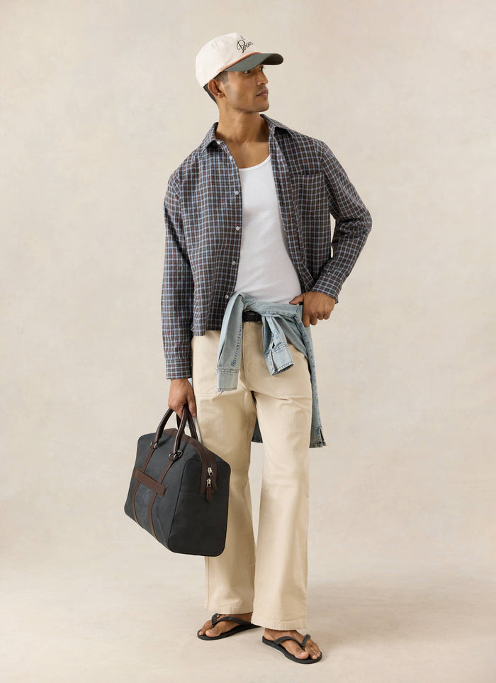 The brown Percival Hinsley cotton boxy shirt in a micro check pattern, styled open over a white vest on a model.