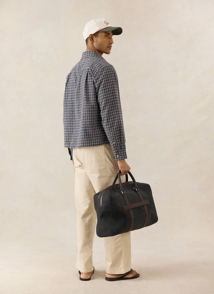 Percival Hinsley brown micro check boxy cotton shirt, viewed from the back on a model with beige trousers and a bag.