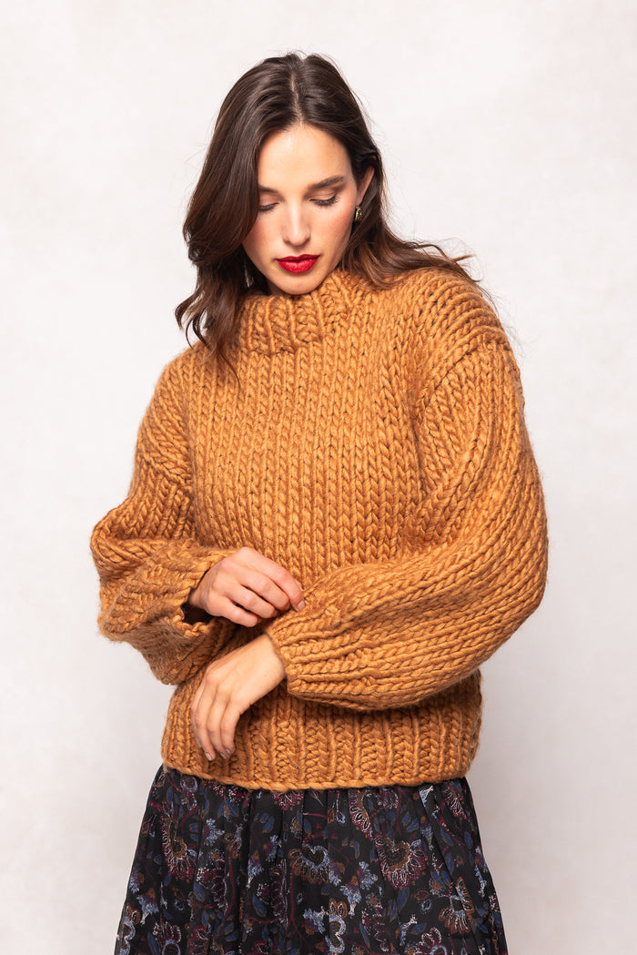 Woman wearing a mustard yellow sweater against a white background