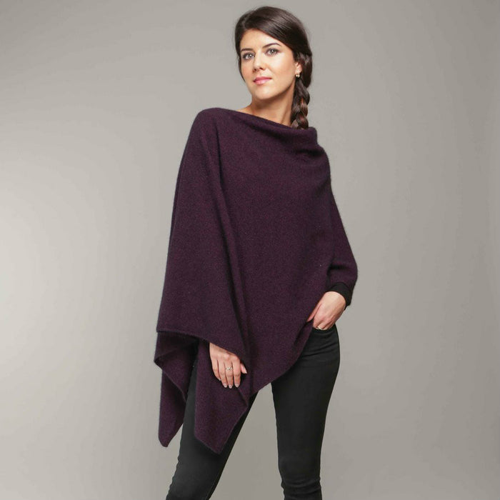 A woman standing wearing a grape-coloured Koru merino and possum Two Way Poncho.