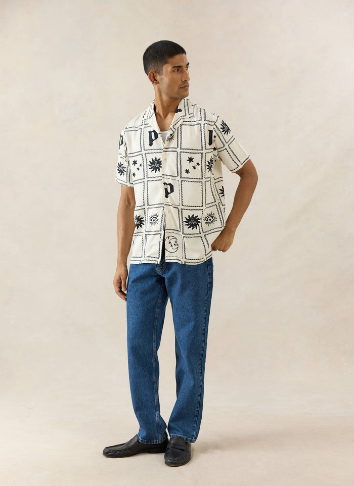 The cream Percival Lunar Panel Cuban Shirt in viscose, featuring black celestial graphics, worn by a model.