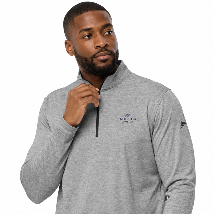 A man wearing a heather gray quarter-zip pullover sweatshirt with a dark blue 'ATHLETIC UNIVERSITY' logo on the left chest and a dark blue logo on the right sleeve, set against a plain white background.