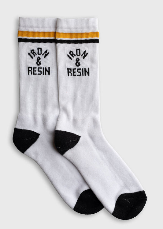 White socks with black toes and heels, featuring "Iron & Resin" text and yellow-black stripes on the cuffs, laid flat on a surface.