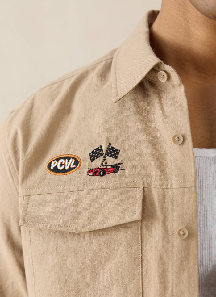 Beige cotton-hemp Percival x Ford shirt featuring racing car and chequered flag embroidery on the chest pocket.