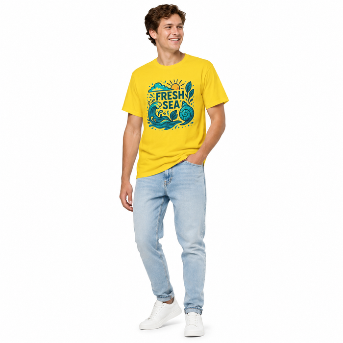 A man wearing a bright yellow graphic t-shirt with a blue and green 'FRESH SEA' design, paired with light blue jeans and white sneakers, standing against a plain white background.