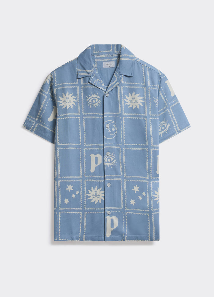 Percival Panels Shirt in light blue, a boxy short-sleeved camp collar shirt with a sun and moon print, shown flat.