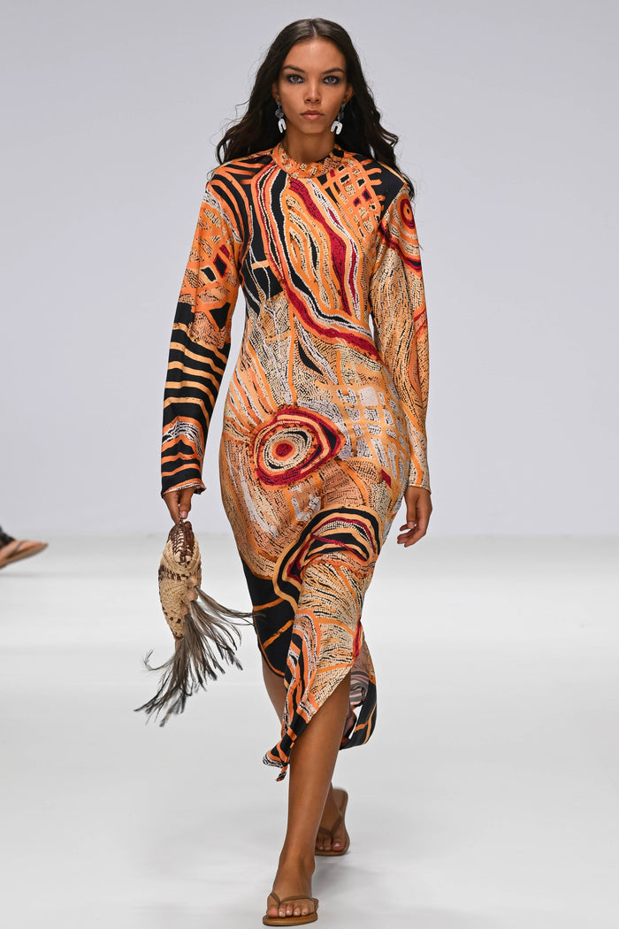 Model walking on a runway wearing a Aboriginal artwork dress.