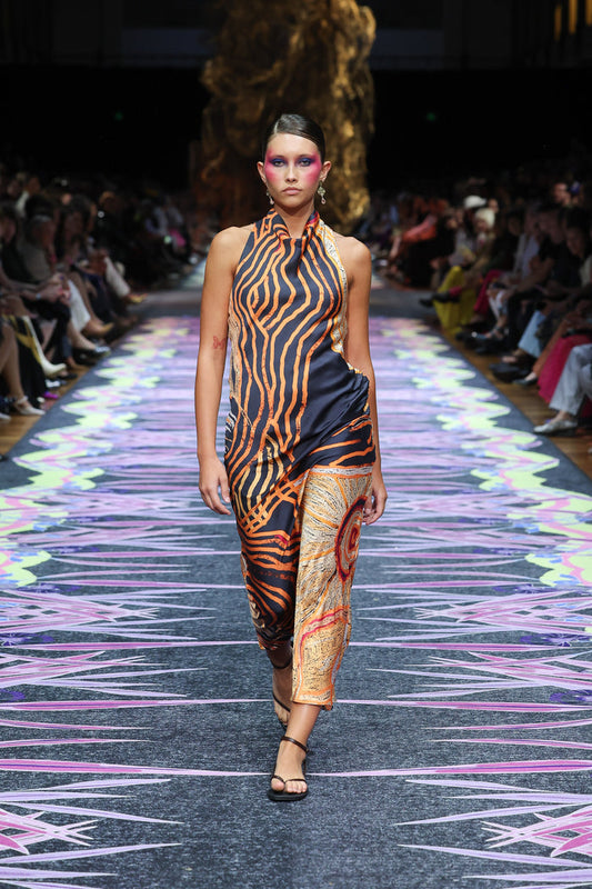 Aboriginal Woman in a First Nations designed dress walking down a runway