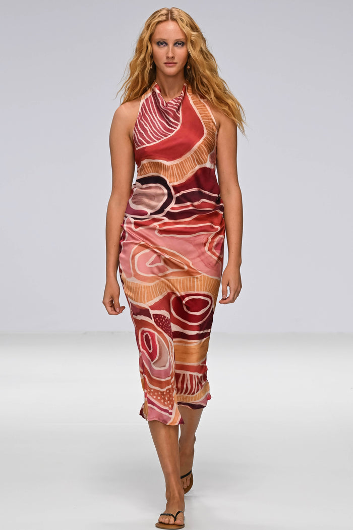 A Woman in a First Nations designed dress walking down a catwalk