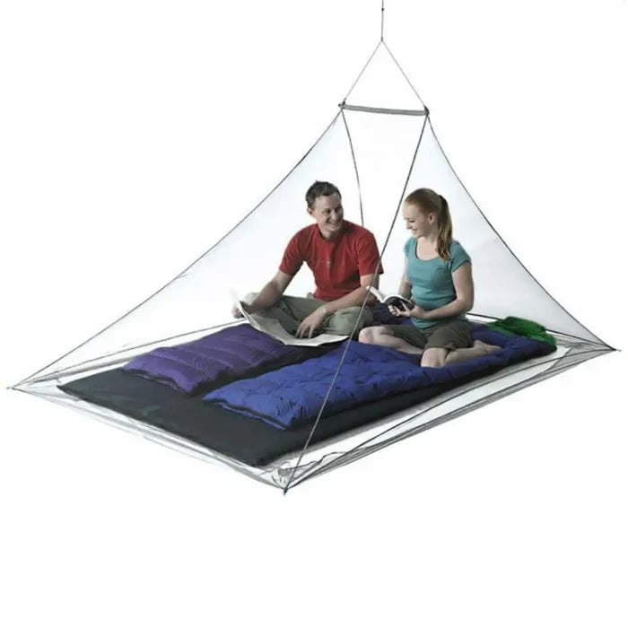 Sea To Summit Pyramid Double Mosquito Net set-up with two people sitting inside on a white background