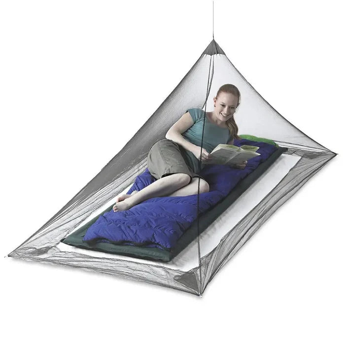 Sea To Summit Pyramid Single Mosquito Net set-up with a woman lying inside protected on a white background