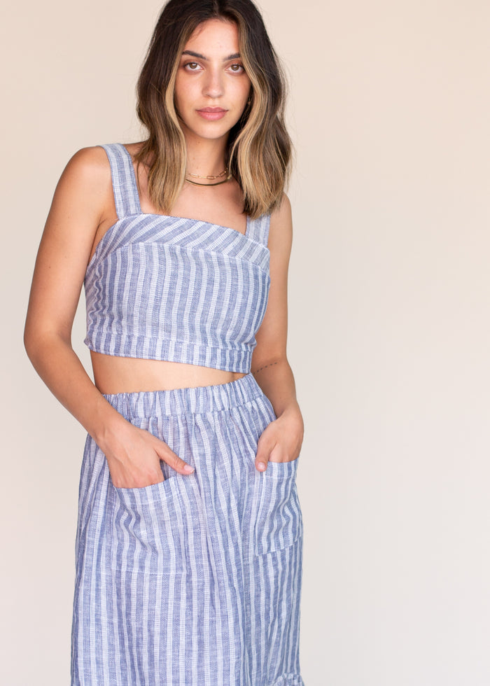 Woman wearing a blue and white striped outfit against a beige background