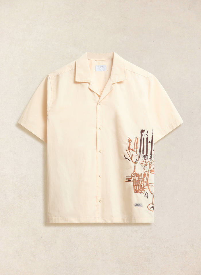 The Percival Supper Club embroidered Cuban shirt in cream, laid flat to showcase the dinner-party illustration.