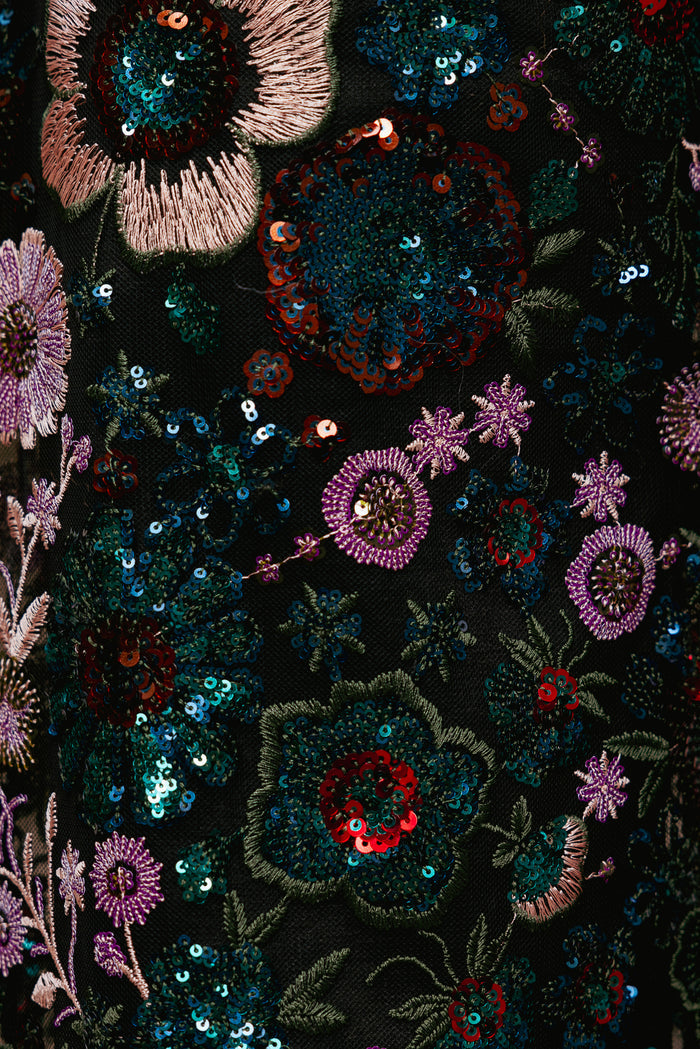 Close-up of a black fabric with colorful floral embroidery and sequins.