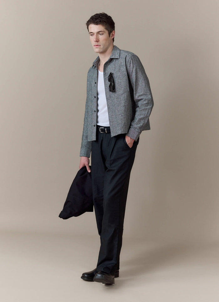 A model wears the Percival Textured Boxy Shirt in grey, layered over a white vest and styled with black trousers.