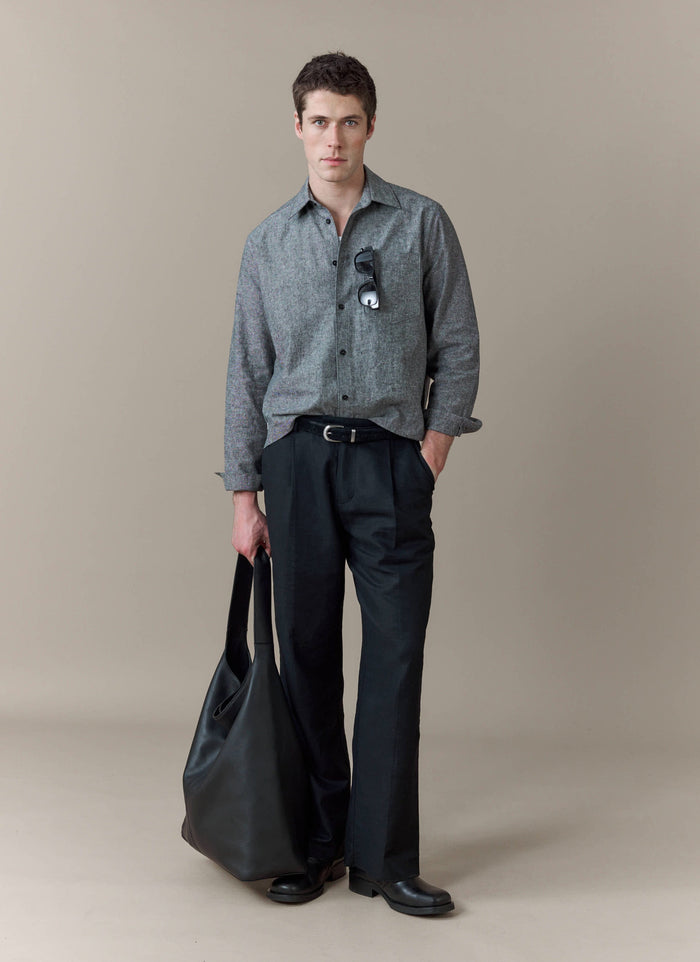 A model wears the Percival Textured Boxy Shirt in grey, styled with smart black trousers and holding a black leather bag.