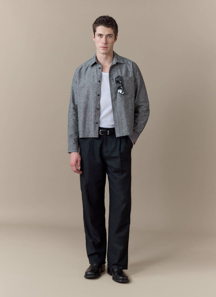 A model wears the grey Textured Boxy Shirt from Percival, styled with a white vest and smart black trousers.