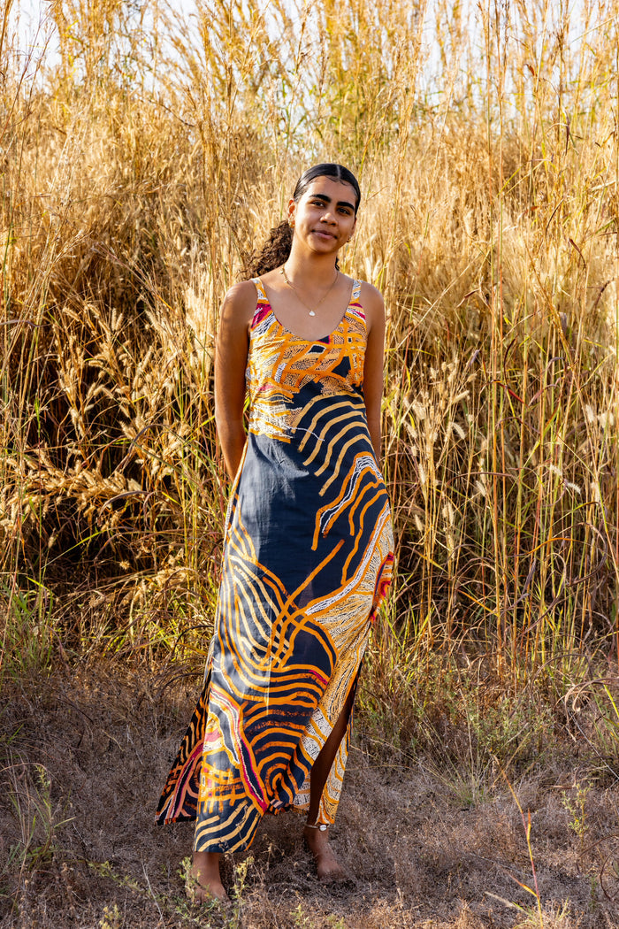 Woman in a Aboriginal patterned dress standing in tall golden grass