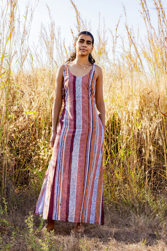 Woman in a Aboriginal patterned dress standing in tall grass