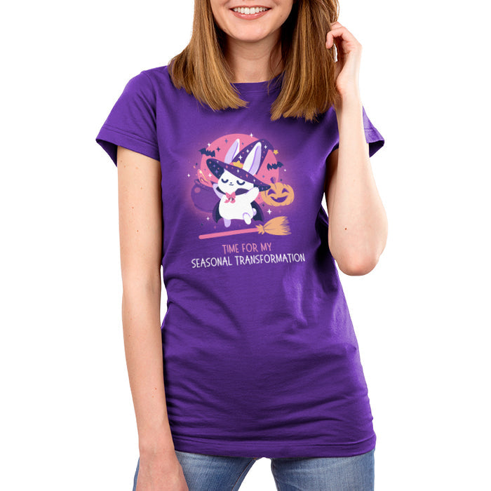 Premium Cotton T-shirt_TeeTurtle purple Time For My Seasonal Transformation apparel featuring a white bunny wearing a sparkling purple witch hat and cloak on top of a flying broom with a cauldron, bats, jack-o'-lantern, and the full red moon in the background.