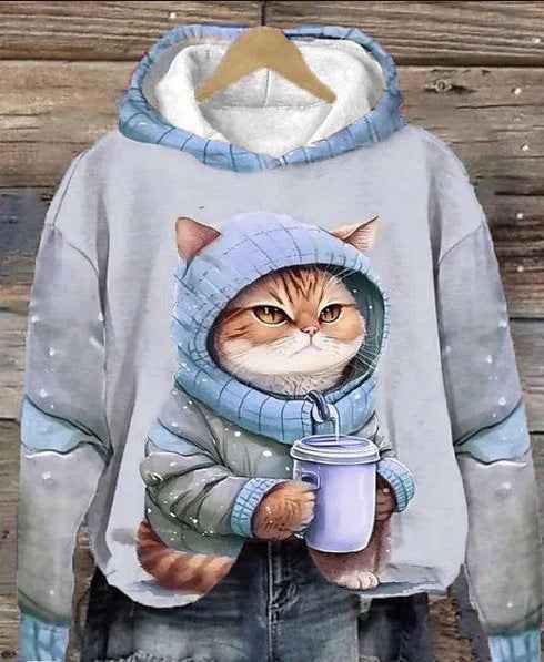 Hoodie with a cat design holding a cup on a wooden background